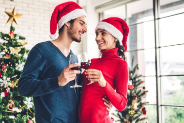 Noel Baba şapkalı romantik çift eğleniyor ve şarap içiyor.