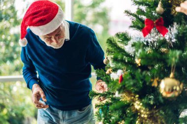 Kıdemli adam Noel ağacını süsler ve gülümserken