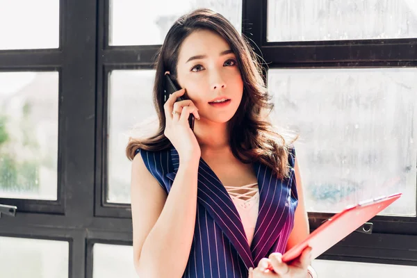 Businesswoman working and using mobile phone while standing in o — Stock Photo, Image