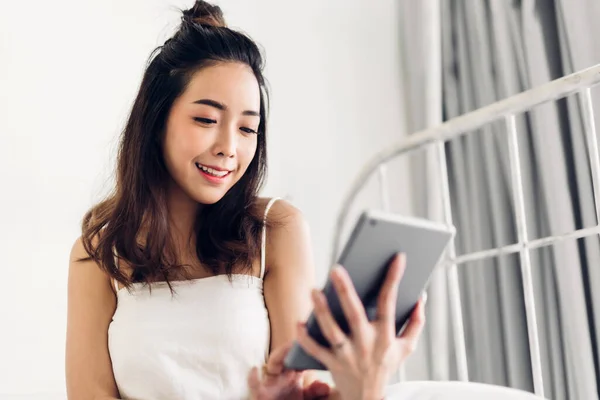 Mujer feliz que relaja usando el ordenador tableta en la cama en home.te — Foto de Stock