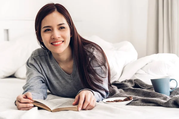 Mujer joven relajante y lectura libro en la cama en casa —  Fotos de Stock