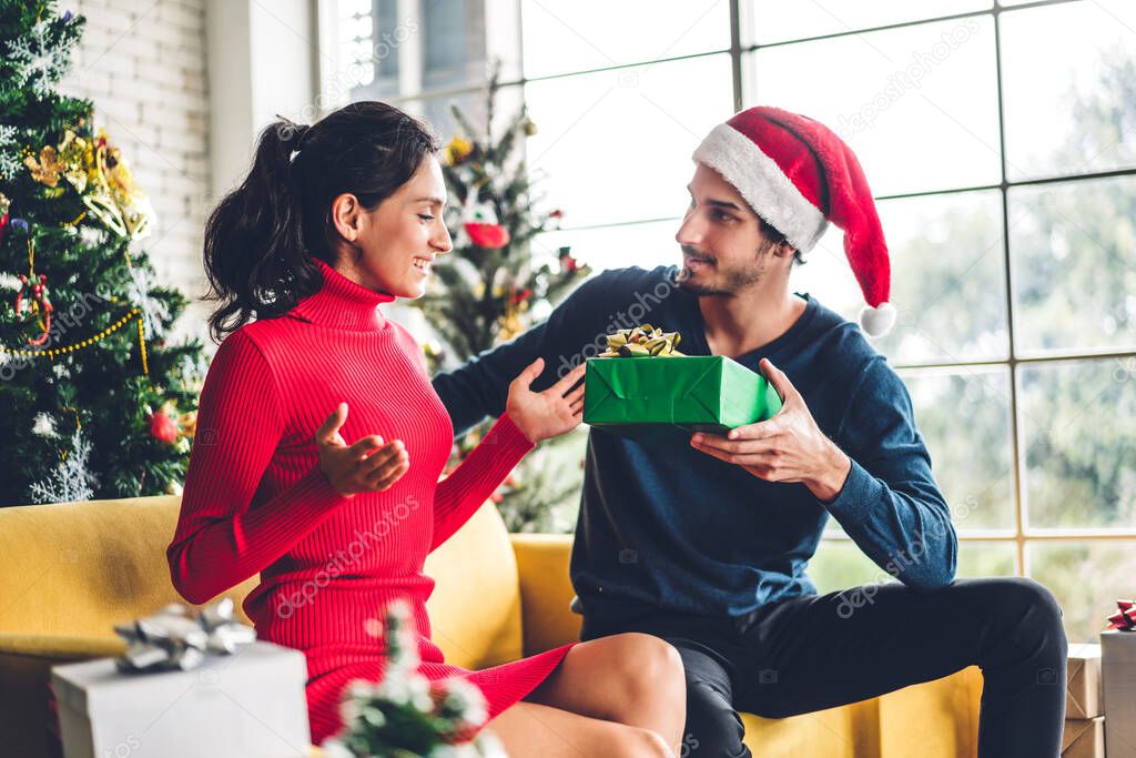 Romantic sweet couple in santa hats having fun decorating christ