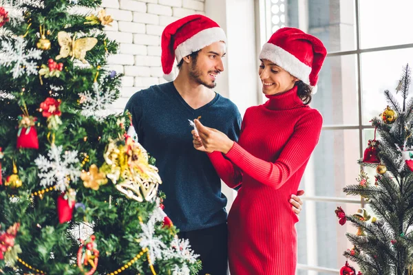 Casal doce romântico em chapéus de santa se divertindo decorando cristo — Fotografia de Stock