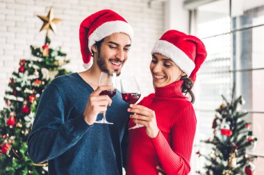 Noel Baba şapkalı romantik çift eğleniyor ve şarap içiyor.