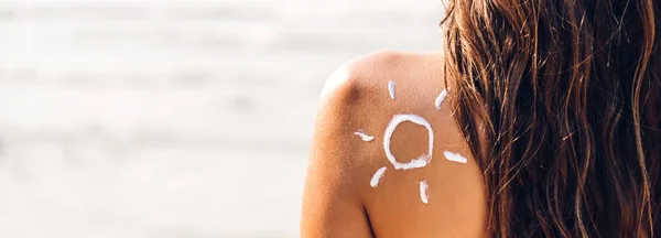 Mujer con bikini de dos piezas aplicando crema solar con sol dibujado —  Fotos de Stock