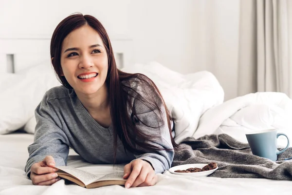 自宅でベッドでリラックスして本を読む若い女性 — ストック写真