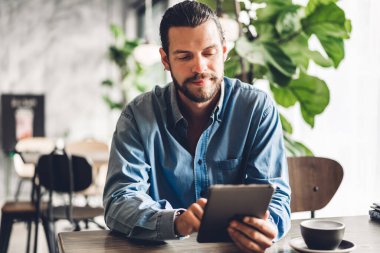 Yakışıklı sakallı hipster adam tablet bilgisayar whil kullanarak rahatlatıcı