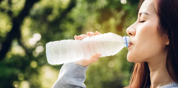 Vacker Asien kvinna dricksvatten från en flaska medan du kopplar av — Stockfoto