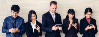 Bir grup iş adamı, akıllı telefon teknolojisini birlikte kullanıyor.