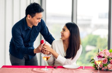 Genç yakışıklı adam sevgilisine sürpriz yapmak için yüzük veriyor ve restoranda konuşuyor.