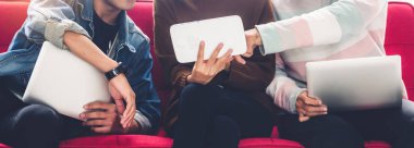 Bir grup arkadaş oturup rahatlarken dizüstü bilgisayar ve tablet teknolojisini kullanarak sosyal uygulamaları ve işi kontrol ediyorlar. İletişim konsepti