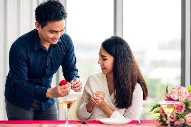 Genç yakışıklı adam sevgilisine sürpriz yapmak için yüzük veriyor ve restoranda konuşuyor.