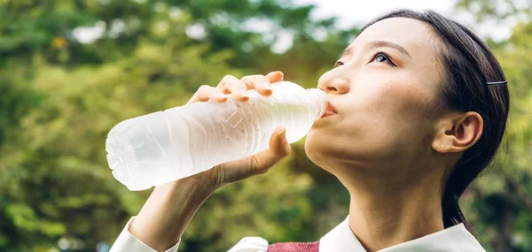 在夏天的绿色公园里 美丽的亚洲女人一边喝着瓶子里的水 一边在绿色的自然背景上放松和感觉新鲜 健康生活方式概念 — 图库照片