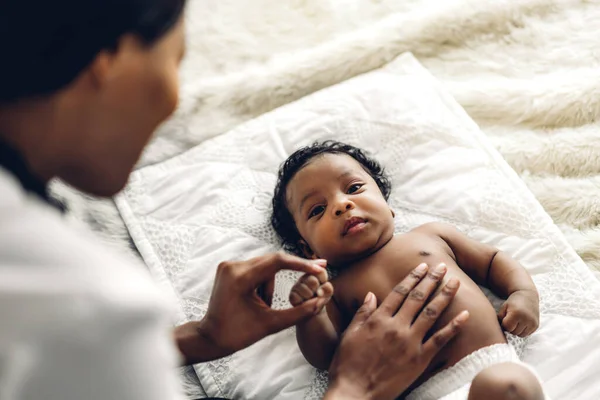白い寝室でかわいいアフリカ系アメリカ人の赤ちゃんと遊ぶアフリカ系アメリカ人の母親 — ストック写真