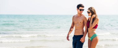 Romantik aşıklar genç mutlu çift deniz kenarında el ele yürüyor ve tropik plajlara metin eklemek için fotokopi çekiliyor. Yaz tatilleri ve seyahatler