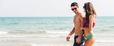 Romantik aşıklar genç mutlu çift deniz kenarında el ele yürüyor ve tropik plajlara metin eklemek için fotokopi çekiliyor. Yaz tatilleri ve seyahatler