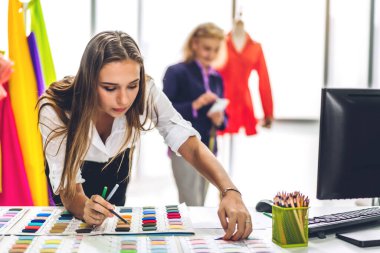 Moda tasarımcısı güzel bir kadının portresi renkli tekstil örnekleriyle çalışıyor. Mankenler ve renkli kumaşlarla çalışan son sınıf öğrencisi bir kadın.