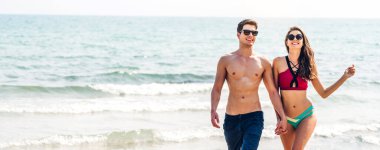 Romantik aşıklar genç mutlu çift deniz kenarında el ele yürüyor ve tropik plajlara metin eklemek için fotokopi çekiliyor. Yaz tatilleri ve seyahatler