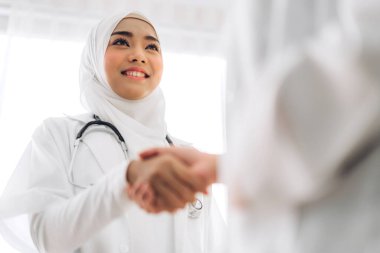 İki Asyalı Müslüman ortağın birlikte gülümsemesi doktor kadın tokalaşması. Profesyonel Müslüman doktor buluşması ve hastanede el sıkışması. Sağlık ve tıp.