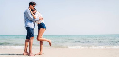 Romantik aşıklar. Genç mutlu çift, tropik plajlara metin eklemek için denizde kumsalda sarılıp eğleniyor ve birlikte rahatlıyor.