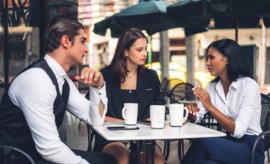 Bir grup neşeli genç arkadaş buluşmayı tartışıyor ve birlikte kahve içerek eğleniyorlar. Kafe masasında ve restoranda karışık ırkçı insanlar oturuyor.