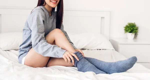 Γυναίκα Κάθεται Στο Κρεβάτι Φορώντας Και Βάζοντας Μεγάλες Ζεστές Κάλτσες — Φωτογραφία Αρχείου