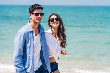 Romantik aşıklar genç mutlu çift deniz kenarında el ele tutuşup tropik sahillerde eğleniyorlar. Yaz tatilleri ve seyahatler.