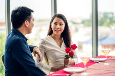 Genç yakışıklı adam sevgilisine kırmızı gül sürprizi yapıyor ve sevgililer gününde elinde çiçek tutuyor.