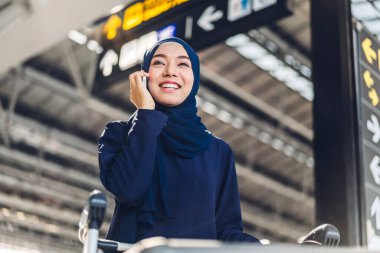 Gülümseyen mutlu müslüman kadının portresi dijital akıllı telefon kullanarak rahatlıyor. Genç müslüman kız telefonda arkadaşıyla konuşuyor.