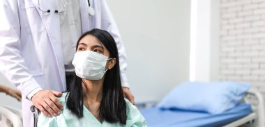 Erkek doktor servisi, maske takan ve sağlık hizmetleri ile görüşmede el ele tutuşan kadın hastalarla konuşma ve danışmanlık konuşmalarını desteklemeye yardımcı olur.