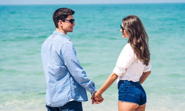 休暇ロマンチックな恋人若い幸せなカップル抱擁と砂の上に立って 熱帯のビーチで一緒に楽しくリラックスしている海を見てください 夏の休暇 — ストック写真