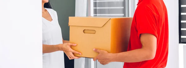 Jovem Mensageiro Homem Entrega Uniforme Vermelho Segurando Uma Caixa Papelão — Fotografia de Stock