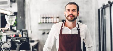 Bir kafede tezgah bar arkasında gülümseyen yakışıklı sakallı barista adam küçük işletme sahibi portresi