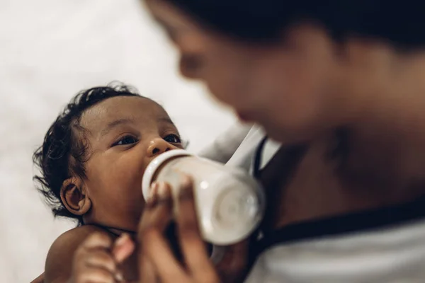 幸せな愛の家族の肖像画アフリカ系アメリカ人の母親は愛らしい小さなアフリカ系アメリカ人の赤ちゃんと遊んでいます 白い寝室でかわいい息子を赤ちゃんにミルクの母供給ボトル 黒の家族の概念の愛 — ストック写真