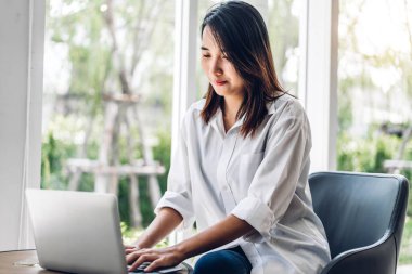 Gülümseyen mutlu Asyalı bir kadının portresi dizüstü bilgisayarını kullanarak rahatlıyor. Genç hippi kız serbest çalışıyor ve kafeteryada ve restoranda yeni fikirler üretiyor.