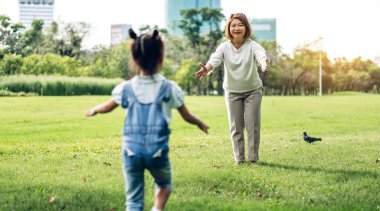 Mutlu büyükanne ve küçük sevimli kız Portresi yaz parkı birlikte dinlenmek keyfini çıkarın, küçük kız büyükanne ve sarılmak için çalıştırın. Aile ve birliktelik