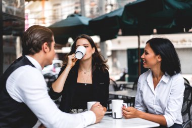 Bir grup neşeli genç arkadaş buluşmayı tartışıyor ve birlikte kahve içerek eğleniyorlar. Kafe masasında ve restoranda karışık ırkçı insanlar oturuyor.