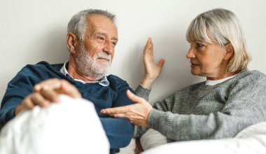 Üst düzey mutlu çift evde yatak odasında uzanıp sohbet ediyor. Emekliler konsepti.