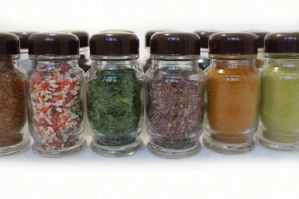 Especiarias em frascos de vidro em um fundo branco — Fotografia de Stock