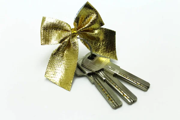 Beyaz zemin üzerinde bir hediye yay ile metal anahtarlar demet. — Stok fotoğraf