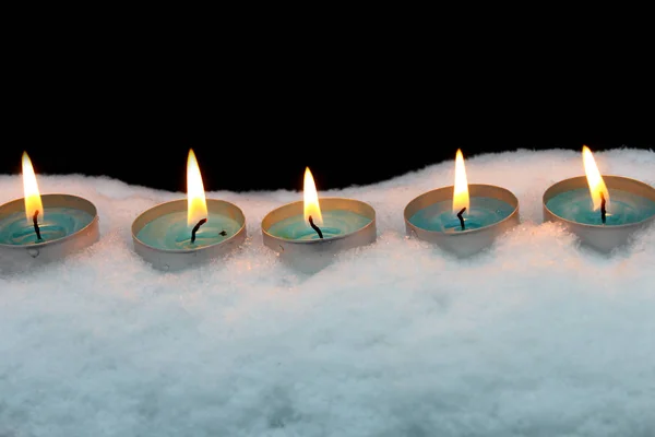 Las velas azules arden en la nieve sobre un fondo negro — Foto de Stock