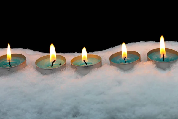 Las velas azules arden en la nieve sobre un fondo negro — Foto de Stock