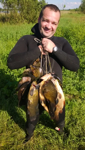 Рыбалка. Человек в водолазном костюме с большой рыбой в руках . — стоковое фото
