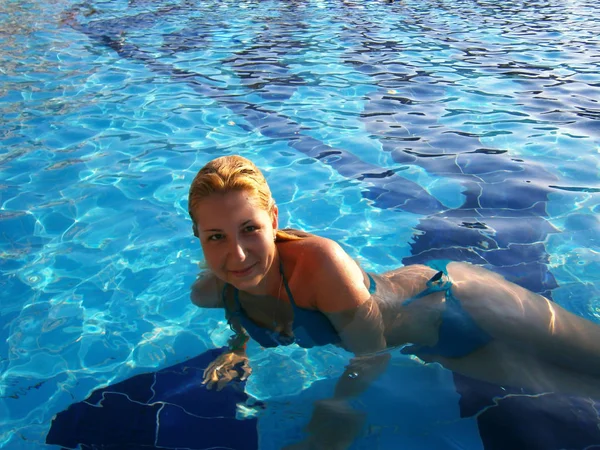 Молода жінка плаває в блакитному басейні — стокове фото