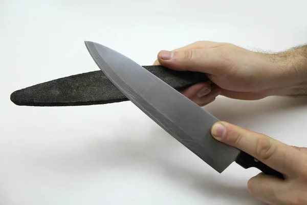 Hands with a grindstone and a knife isolated on a gray background — Stock Photo, Image