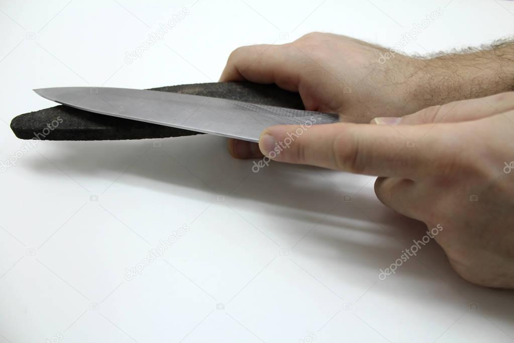 Hands with a grindstone and a knife isolated on a gray background