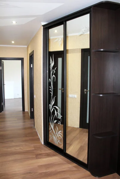 Koridorda cam kapı sürgülü ile kahverengi gardırop. 