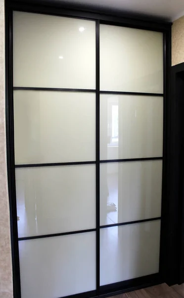 Brown wardrobe with white glass sliding doors — Stock Image Brown wardrobe with white glass sliding doors Stock Photo
