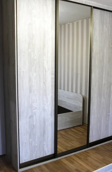 Grey wardrobe with sliding glass doors in the hallway.