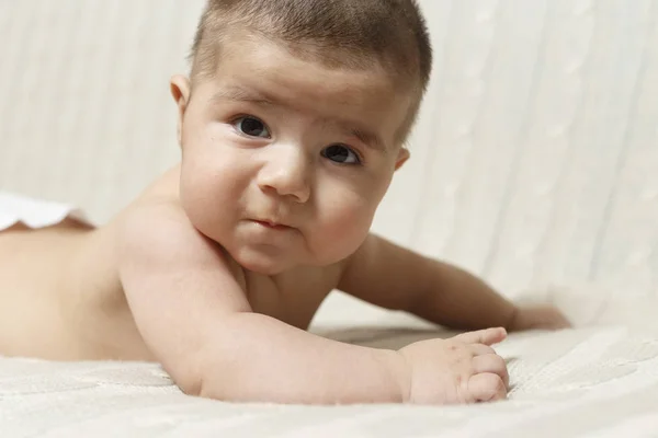 4 aylık bir erkek bebek karnı üzerinde evde yatıyor